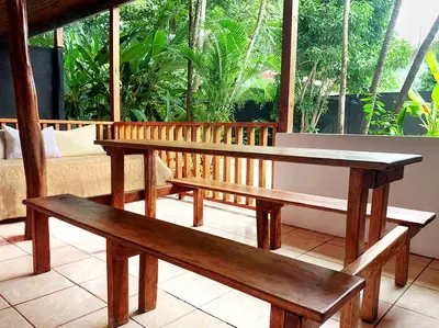 two wooden benches sitting on a porch with a table at ICO Living Hostel in Santa Teresa Beach