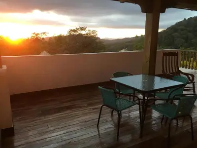 a table and chairs on a deck with the sunset at Hacienda Las Vainillas Boutique Hotel in Mastatal