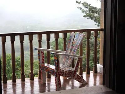 a rocking chair sitting on a balcony with a view at Hacienda Las Vainillas Boutique Hotel in Mastatal
