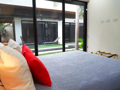 a bedroom with a large bed with red pillows at Playa Potrero - NEW modern house, pool in guitar shape - Casa Guitarra in Potrero