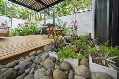 a garden with rocks and a wooden deck at Playa Potrero - NEW modern house, pool in guitar shape - Casa Guitarra in Potrero