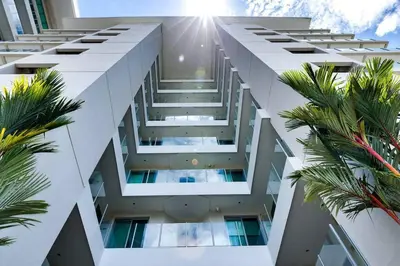 a tall white building with palm trees in front of it at Diamante del Sol 202N - 2nd Floor Ocean View in Jacó