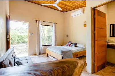 a bedroom with a bed and a large window at Apartamento el Guanacaste, cerca Tamarindo con Piscina in Santa Cruz