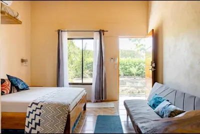 a bedroom with a bed and a couch and a window at Apartamento el Guanacaste, cerca Tamarindo con Piscina in Santa Cruz