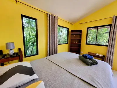 a bedroom with a large bed with yellow walls and windows at Villa Martina Palmgarden in Sámara