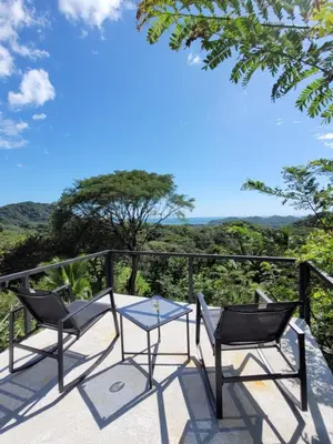 a patio with two chairs and a table on a balcony at Villa Martina Palmgarden in Sámara
