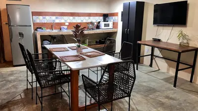 a dining room with a table and chairs and a kitchen at Apartamento los Guanacastes cerca de Tamarindo con piscina in Santa Cruz