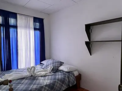 a bedroom with a bed and a window with blue curtains at Twin Palms house in Monteverde Costa Rica