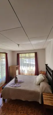 a bedroom with a large bed with red curtains at Twin Palms house in Monteverde Costa Rica