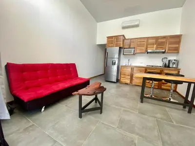 a living room with a red couch and a kitchen at Canavida Villas & Resort in Uvita