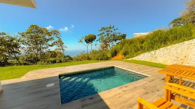 a swimming pool with a table and a chair at Canavida Villas & Resort in Uvita