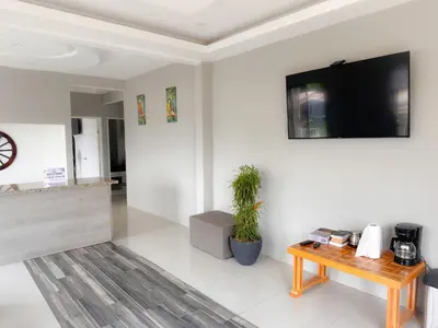 a living room with a table and a tv on a wall at Casa Garitas GuestHouse & Car Rental - Free SJO Airport Shuttle - Nationwide Private Shuttle Services - casagaritas com in Santiago Este