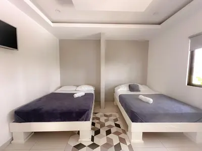 two twin beds in a room with a tv at Casa Garitas GuestHouse & Car Rental - Free SJO Airport Shuttle - Nationwide Private Shuttle Services - casagaritas com in Santiago Este