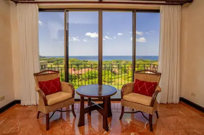 a room with two chairs and a table in front of a window at Luxurious 3BR Ocean-View Condo - Malinche - Reserva Conchal in Playa Conchal
