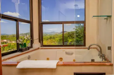a bath tub in a bathroom with windows at Luxurious 3BR Ocean-View Condo - Malinche - Reserva Conchal in Playa Conchal