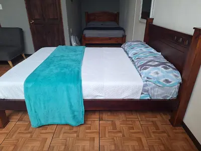 a bedroom with a bed with a blue blanket on it at Anchia - Hostel in Alajuela City