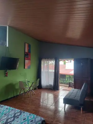 a living room with green walls and a table and chairs at Anchia - Hostel in Alajuela City