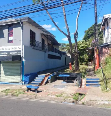 a train sitting outside of a building with benches at Anchia - Hostel in Alajuela City