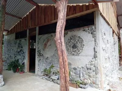 a building with a stone wall with a window at Cabaña Eco-Arte in Tortugal