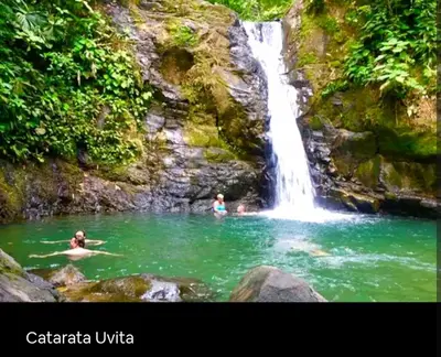 two people swimming in a pool in front of a waterfall at Cabaña Eco-Arte in Tortugal