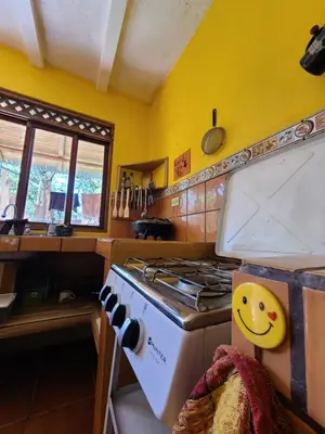 a kitchen with a stove and a yellow wall at Casa Terra Hostel in Sámara
