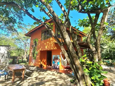 an orange house with a tree in front of it at Casa Terra Hostel in Sámara