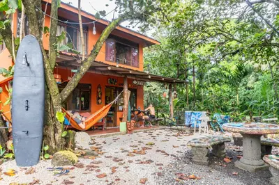 a house with a surfboard in front of it at Casa Terra Hostel in Sámara
