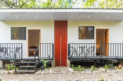 a house with a red door and chairs on a balcony at Casa Terra Hostel in Sámara