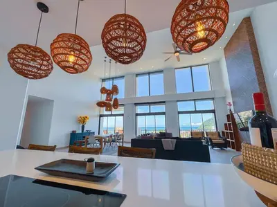 a living room with many windows and pendant lights at Elegant Oceanview Penthouse - Steps from Jaco Beach & Nightlife in Jacó