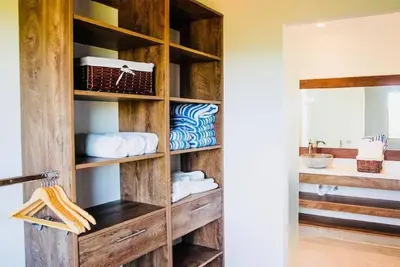 a bathroom with a wooden book shelf with towels at Elegant Oceanview Penthouse - Steps from Jaco Beach & Nightlife in Jacó