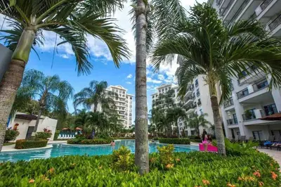 a resort with palm trees and a swimming pool at Elegant Oceanview Penthouse - Steps from Jaco Beach & Nightlife in Jacó