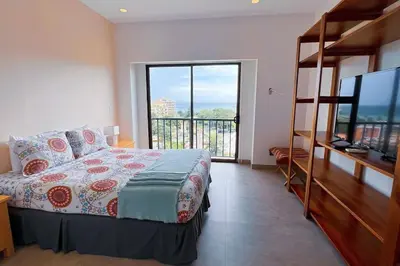 a bedroom with a bed and a large window at Elegant Oceanview Penthouse - Steps from Jaco Beach & Nightlife in Jacó