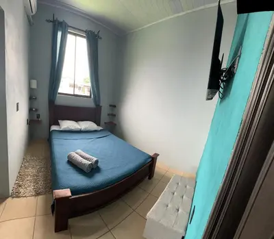 a bedroom with a bed with blue sheets and a window at Los Sueños IyE 4 in Quepos
