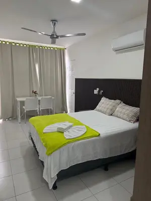 a bedroom with a bed with a green blanket on it at Hotel Sabana Inn in San José