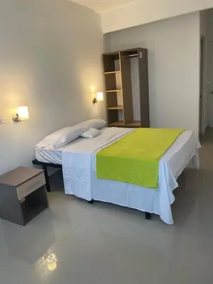 a bedroom with a bed with a green blanket on it at Hotel Sabana Inn in San José