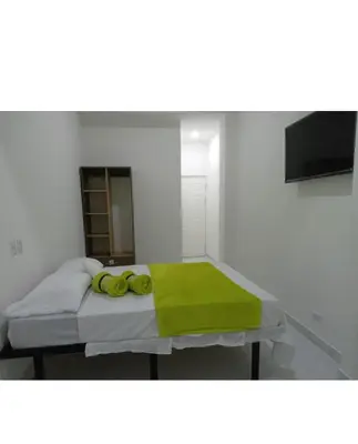 a bed with a green blanket and two yellow objects on it at Hotel Sabana Inn in San José