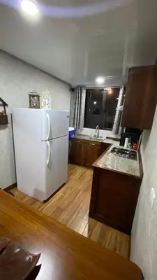 a kitchen with a white refrigerator and a wooden floor at Casita Don Eliber in Fortuna