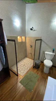 a bathroom with a toilet and a shower with a mirror at Casita Don Eliber in Fortuna