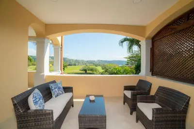 a porch with two chairs and a couch and a table at Colina 7C 3 bdr Garden View in Los Suenos in Herradura