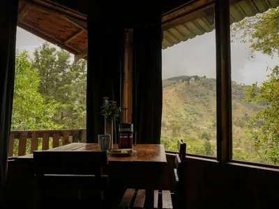 a table and chairs in a room with a large window at Valchi Hospedaje de Montaña in El Copey
