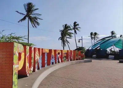 a fence with colorful flags on it next to the ocean at CasaLu in Puntarenas