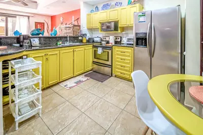 a kitchen with yellow cabinets and a stainless steel refrigerator at Bahia Encantada I1 in Jacó