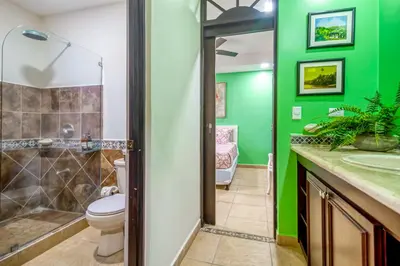 a bathroom with a toilet and a green wall at Bahia Encantada I1 in Jacó