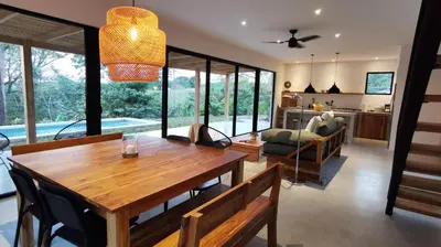 a kitchen and living room with a wooden table and chairs at La Golfina Villa in Santa Teresa Beach