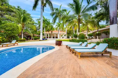 a swimming pool with lounge chairs and palm trees at Club Voca #9 in Coco