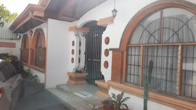 a house with windows and a car parked outside at Mario y Jeannette in Alajuela City