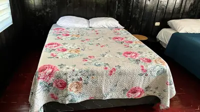 a bed with a blanket with roses on it at Koi's House - Quebradillas de Dota in Santa María