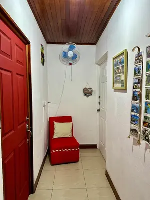 a red chair in a hallway with a red door at Private bedroom 10 minutes from the SJO airport in Alajuela City