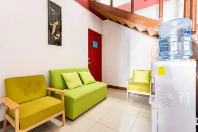 a living room with a green couch and a refrigerator at Private bedroom 10 minutes from the SJO airport in Alajuela City