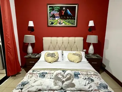 a bedroom with red walls and a bed with two lamps at Private bedroom 10 minutes from the SJO airport in Alajuela City